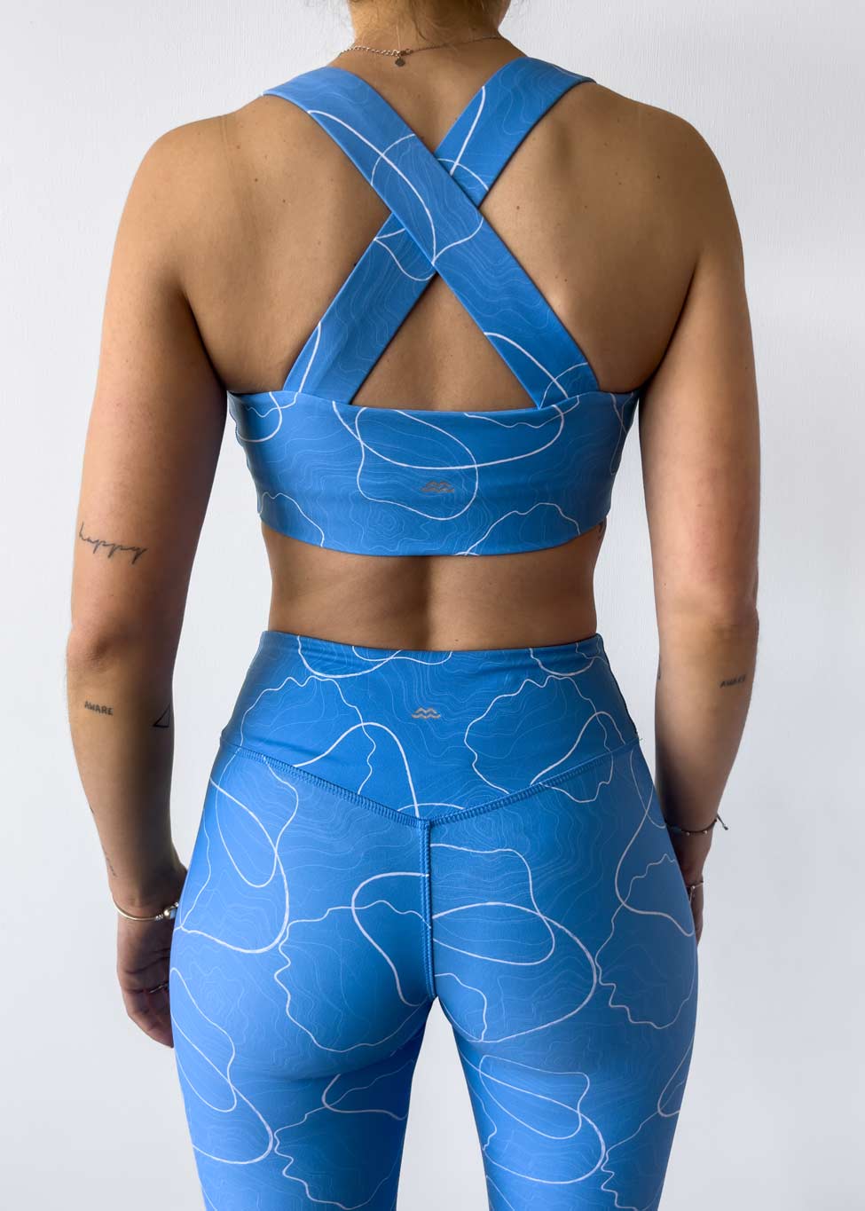 Sujetador diseñado para deportes de impacto medio a bajo, estilo cruzado en la espalda con elástico invisible debajo del busto.  El diseño de este estampado está inspirado en las cotas geográficas de nuestras montañas y el color en el mar. Siéntete cómoda usando este top en tus entrenamientos de gimnasio, box, yoga, pilates, trekking o para tu día a día. Combínalo con los leggings Geo ¡o con lo que quieras!